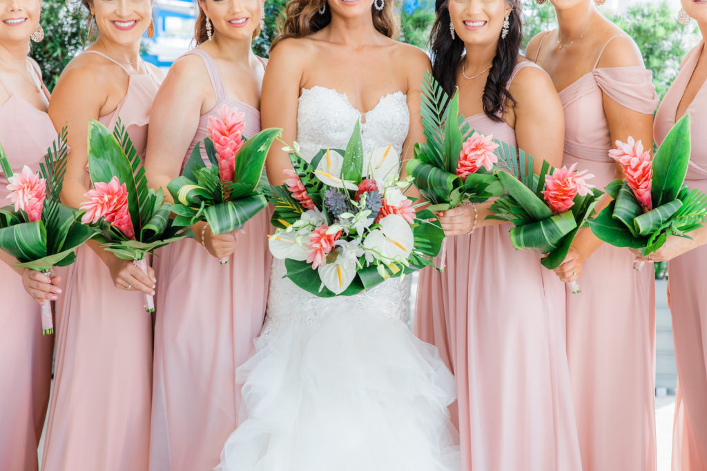 Tampa Bay Bride in Strapless Sweetheart Mermaid Beaded and Lace Wedding Dress with Organza Ruffle Skirt Holding Tropical Floral Bouquet, Pink Ginger, White Anthuriums, Monstera Palm Leaves and Bridesmaids in Pink Mix and Match Dresses | Wedding Venue Hilton Clearwater Beach | Wedding Florist Iza's Flowers