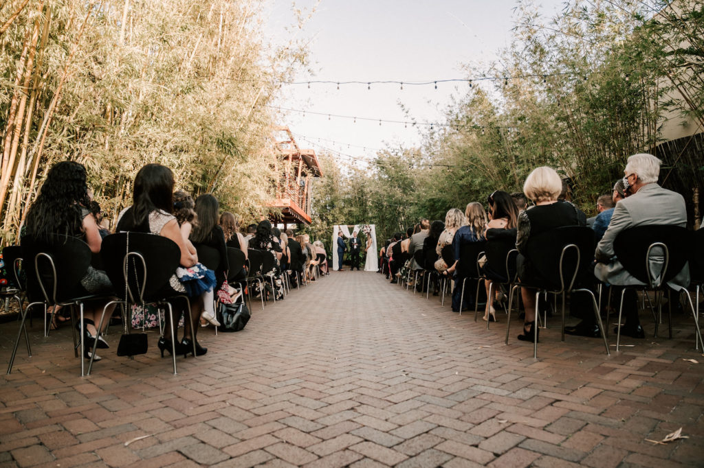 Industrial Inspired Florida Wedding Ceremony in Bamboo Garden Courtyard, Decorated with Romantic Moody Florals, Ceremony Arch with Soft White Draping and Greenery | Tampa Bay's Best Place for a Wedding NOVA 535 in Downtown St. Pete