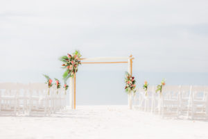 Tropical Wedding Ceremony Decor on the Beach, Bamboo Arch with Colorful Floral Arrangements, White Folding Chairs | Wedding Venue Hilton Clearwater Beach | Wedding Florist Iza's Flowers