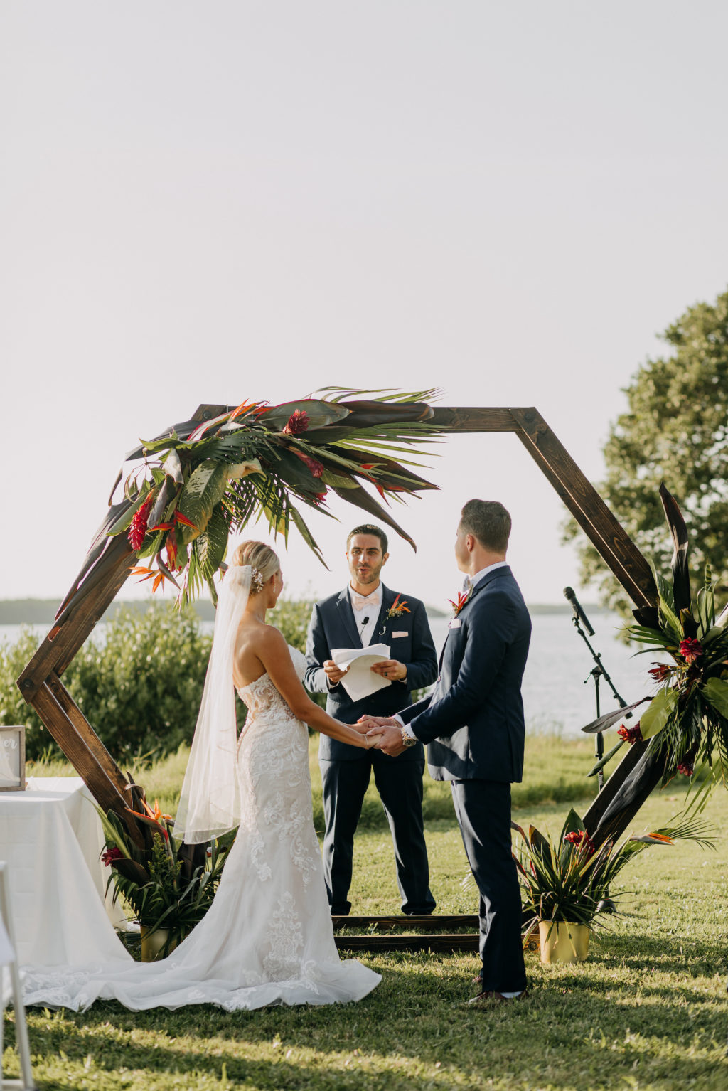 Tropical Elegant Bride and Groom Exchanging Wedding Ceremony Vows, Wooden Geometric Arch with Tropical Floral Arrangement | Tampa Bay Wedding Photographer Amber McWhorter Photography | Waterfront Wedding Venue Tampa Bay Watch