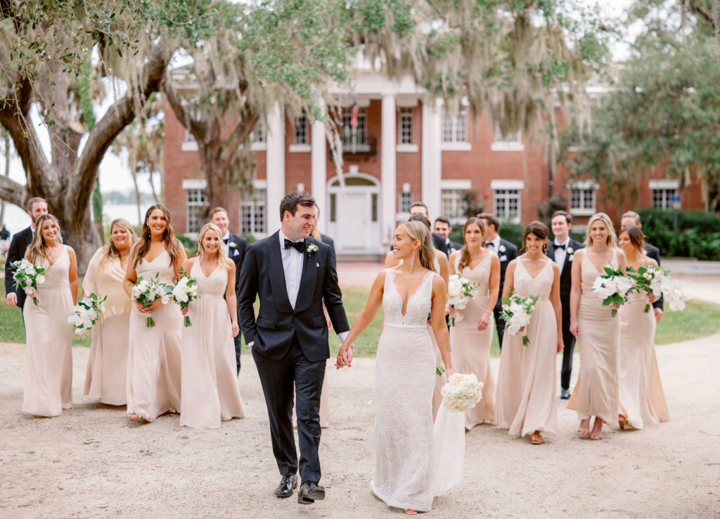 Romantic Luxurious Bride in Jane Hill Luella Beaded Fitted Plunging Scalloped Neckline Wedding Dress with Groom in Black Tuxedo, Bridesmaids in Mix and Match Champagne Dresses and Groomsmen Wedding Party Photo | Wedding Venue Bay Preserve at Osprey