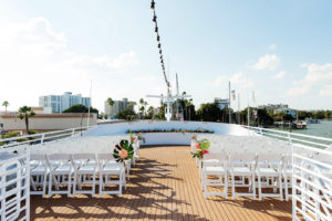 Tropical Waterfront Wedding Ceremony Decor, White Folding Chairs, Monstera Leaves and Pink Flower Arrangements | Tampa Bay Wedding Photographer Limelight Photography | Wedding Venue Yacht StarShip