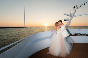 Sunset Romantic Bride in Blush Pink Strapless Princess Ballgown Tulle Skirt Wedding Dress and Groom in White Tuxedo on Deck of Boat | Waterfront Wedding Venue Yacht Starship | Tampa Bay Wedding Photographer Limelight Photography