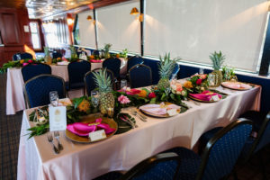 Tropical Wedding Reception Decor, Blush Pink Silk Linen Tables, Gold Chargers with Hot Pink Linen Napkins, Gold Accents, Pineapples and Colorful Flower and Palm Leaves Garland Centerpiece | Waterfront Wedding Venue Yacht StarShip | Tampa Bay Wedding Photographer Limelight Photography
