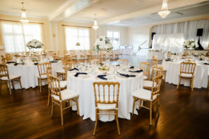 Classic Wedding Reception Decor, Gold Chairs, Round Tables with White Linens, Navy Blue Linen Napkins, Tall White Floral Centerpieces | Tampa Bay Wedding Photographer Lifelong Photography Studio | Wedding Rentals A Chair Affair | Kate Ryan Event Rentals | Wedding Venue The Orlo House| | Wedding Planner Core Concepts