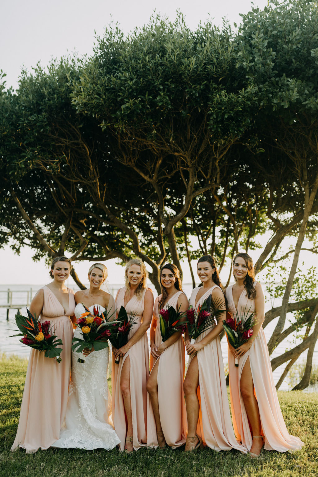 Florida Tropical Elegant Bridesmaids in Matching Blush Pink Dresses with High Leg Slit, Pink Ginger, Orange Birds of Paradise, Yellow and Red Pincushion Protea, Palm Leaves Floral Bouquets | Tampa Bay Wedding Photographer Amber McWhorter Photography