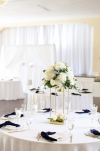 Classic Wedding Reception Decor, White Table Linens, Navy Blue Linen Napkins, Gold Flatware and Stand with White Hydrangeas, Roses and Greenery Floral Centerpiece | Tampa Bay Wedding Photographer Lifelong Photography Studio | Wedding Planner Core Concepts | Wedding Rentals A Chair Affair | Kate Ryan Event Rentals