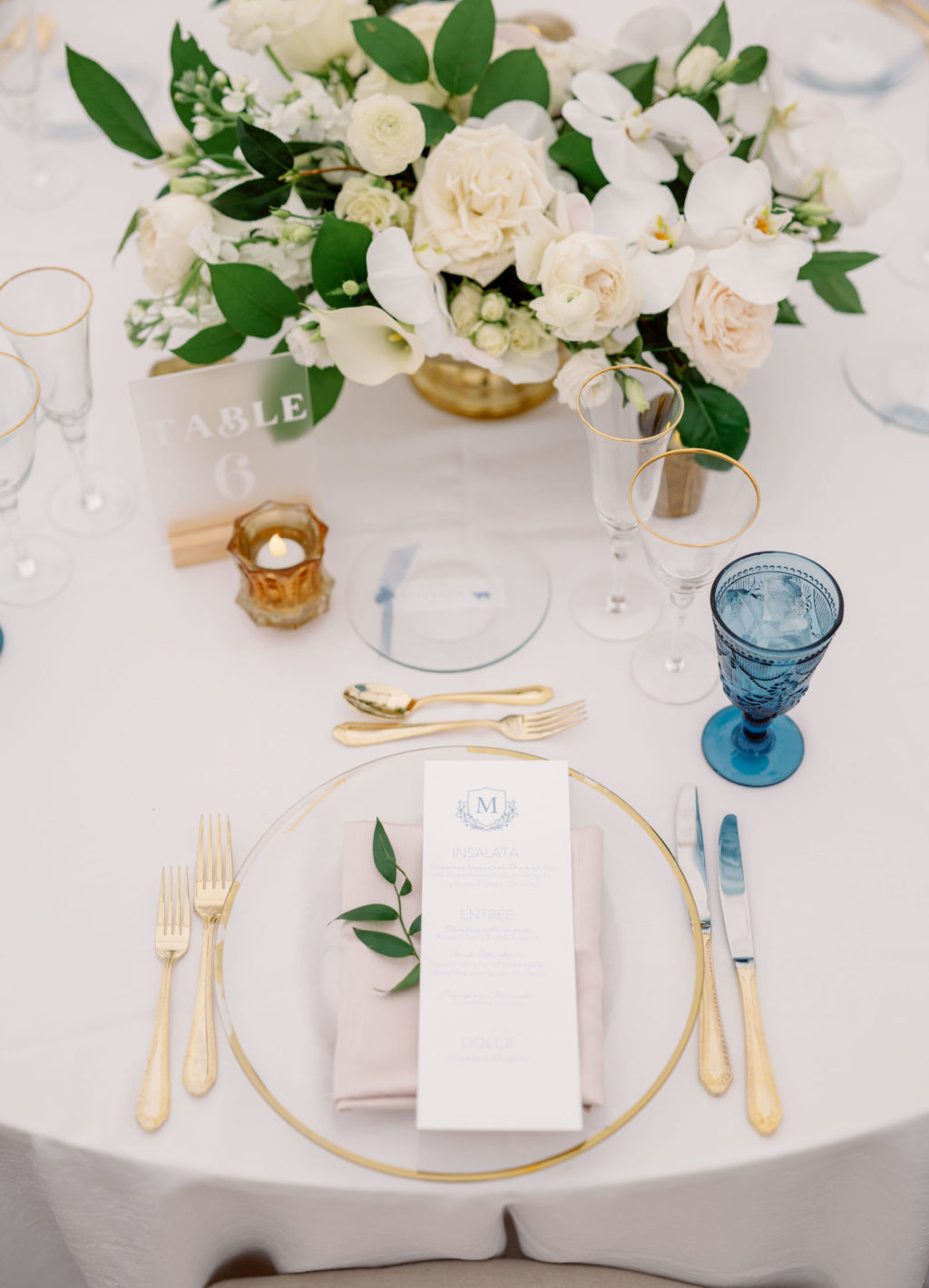 Elegant Luxurious Wedding Reception Decor, Gold Rimmed and Clear Glass Charger, Gold Flatware, Blue Water Goblet, Acrylic Table Number, White Roses, Orchids and Greenery Floral Centerpiece | Tampa Bay NK Productions Wedding Planning