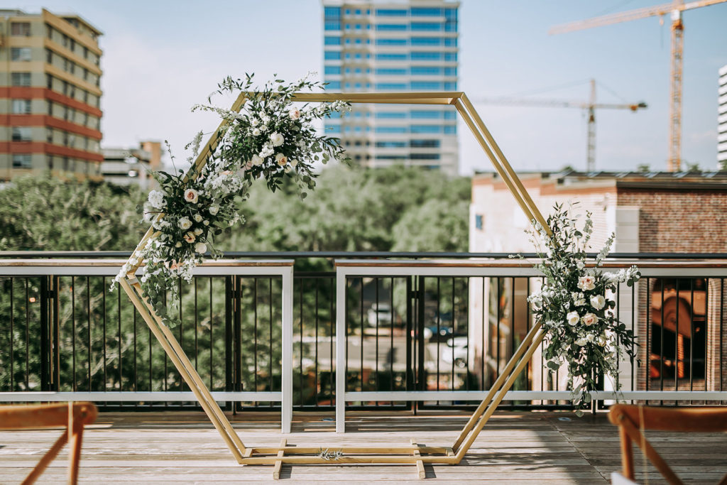 Geometric Gold Arch Ceremony Backdrop with Natural Rustic Floral Spray of White Roses and Eucalyptus Greenery