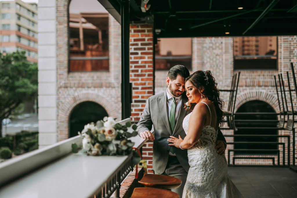Outdoor Rooftop Bride and Groom Portrait at Downtown St. Pete Wedding Venue Red Mesa Events | Groom Wearing Classic Charcoal Grey Suit with Green Tie
