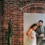 Historic Venue Brick Wall Backdrop Bride and Groom Portrait at Downtown St. Pete Wedding Venue Red Mesa Events | Groom Wearing Classic Charcoal Grey Suit with Green Tie | Perfecting the Plan