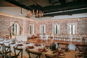 Indoor Historic Venue Brick Wall Wedding Reception at Downtown St. Pete Wedding Venue Red Mesa Events | Cross Back Wood French Country Chairs with White Table Linens on Long Feasting Tables | Perfecting the Plan