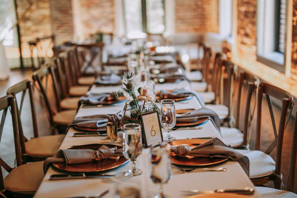 Long Feasting Tables with White Linens and Copper Charger Plates with Taupe Napkins and Wood Cross Back Chairs for Wedding Reception | Perfecting the Plan