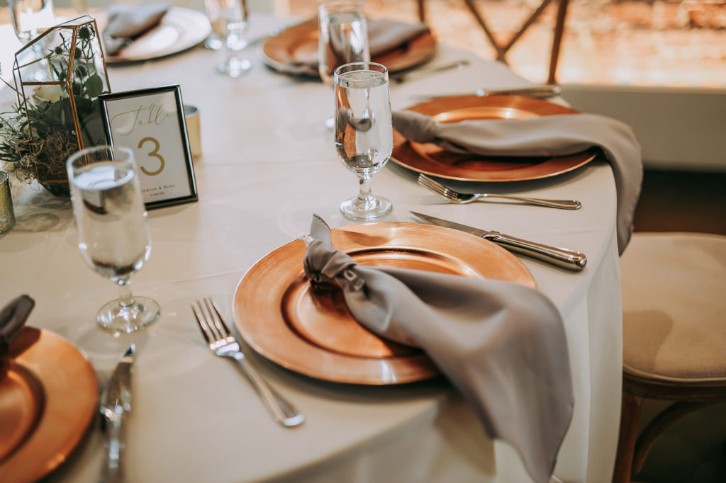Tables with White Linens and Copper Charger Plates with Taupe Napkins for Wedding Reception