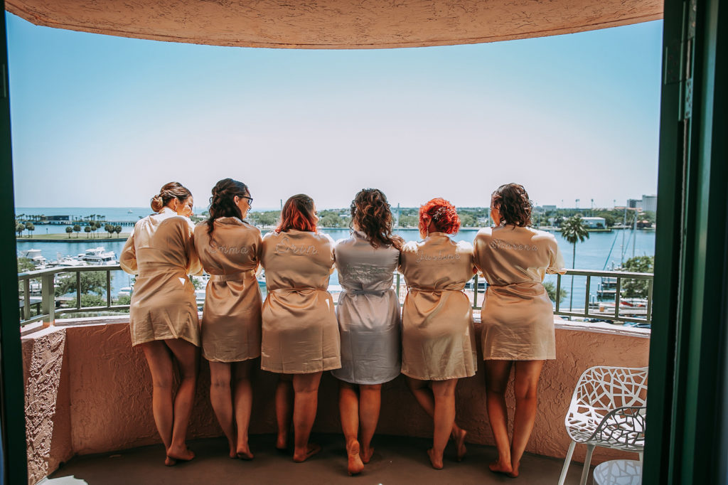 Bride and Bridesmaids Bridal Party Photo on Hotel Room Balcony in St. Petersburg Florida | Bride and Bridesmaids Getting Ready Wearing Champagne and Silver Embroidered Silk Robes