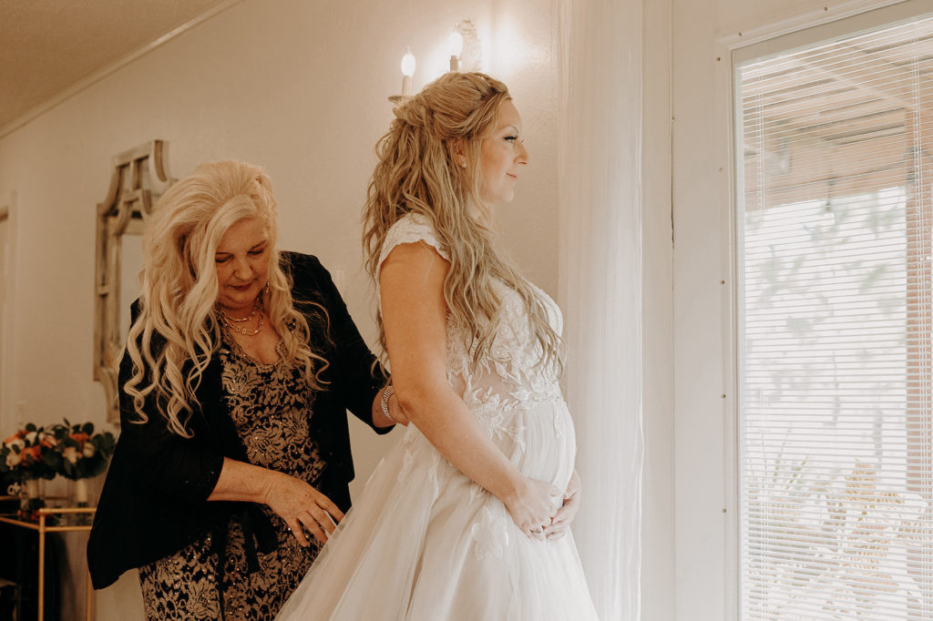 Tampa Pregnant Bride Getting Wedding Ready in Flowy Lace Short Sleeve and Tulle A-Line Wedding Dress with Mom, Hair Half Up with Waves | Plant City Wedding Venue Florida Rustic Barn | Tampa Bay Wedding Hair and Makeup Femme Akoi Beauty Studio