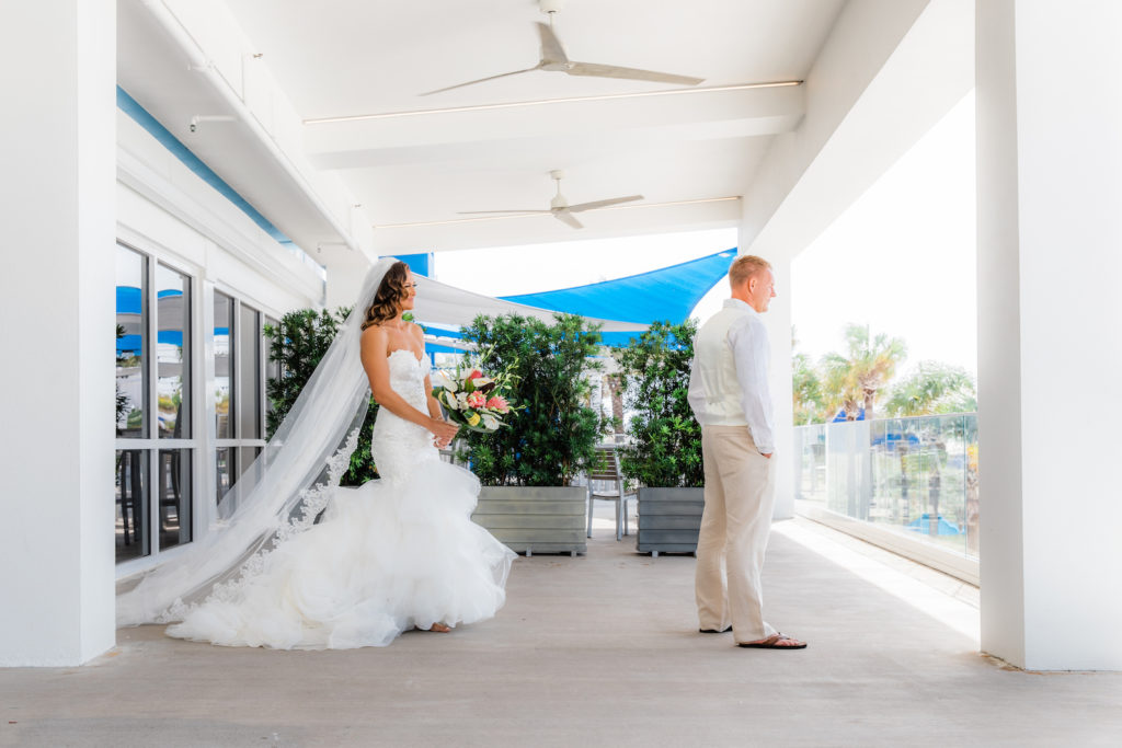 Tampa Bay Bride in Romantic Mermaid Strapless Sweetheart Organza Ruffle Skirt Wedding Dress and Full Length Veil First Look with Groom | Wedding Venue Hilton Clearwater Beach