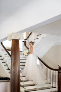 Classic Bride in Tulle Skirt A-Line Wedding Dress Holding White Floral Bouquet on Staircase of Wedding Venue The Orlo | Tampa Bay Wedding Photographer Lifelong Photography Studio