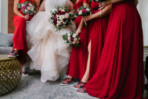 Bride in Ruffle Tulle Skirt Wedding Dress, Bridesmaids in Red Dresses and Floral and Burgundy Rifle Paper Co Sneakers Holding Jewel Tone Floral Bouquets | Tampa Bay Wedding Florist Brides N' Blooms Wholesale Designs