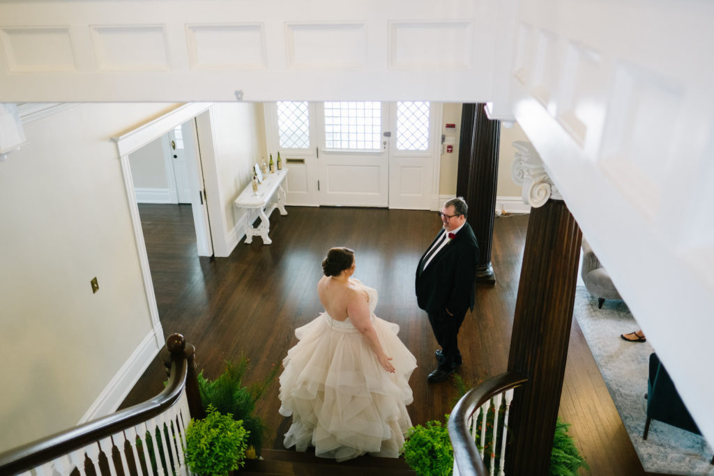 Tampa Bay Bride in Ruffle Tulle Skirt Wedding Dress First Look with Father at Bottom of Stairs in Wedding Venue The Orlo