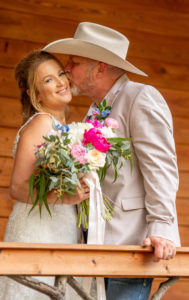 DIY Backyard Tampa Bride Holding Colorful Pink, White, Greenery and Blue Floral Bouquetand Groom in Cowboy Hat