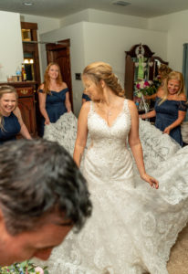 DIY Bride Wearing Lace V Neckline Wedding Dress and Bridesmaids in Navy Blue Dresses Holding Train