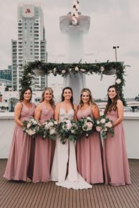 Florida Minimalistic Bride Holding Greenery and White Floral Bouquet with Bridesmaids in Dusty Rose Dresses | Tampa Bay Waterfront Wedding Venue Yacht StarShip | Wedding Hair and Makeup Femme Akoi Beauty Studio | Wedding Photographer and Videographer Bonnie Newman Creative