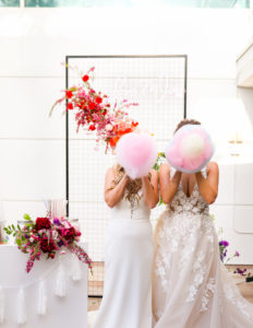 Modern Gay LGBTQ+ Pride Wedding, Lesbian Brides Holding Pink Cotton Candy, Rectangle Black Mesh Grid Arch with Colorful Rainbow Flower Arrangements | Tampa Bay Wedding Planner Stephany Perry Events | Rooftop Wedding Venue Hotel Alba