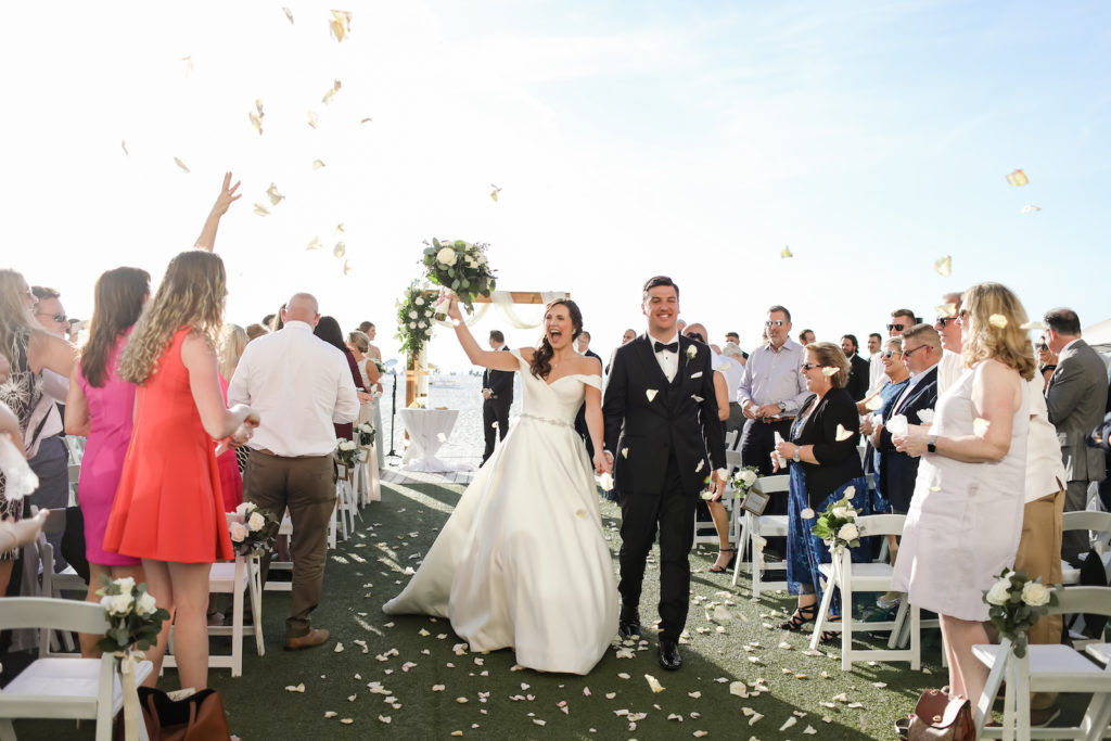 Florida Timeless Bride and Groom Wedding Ceremony Exit Recessional with Guests Throwing White Rose Petals on Waterfront Lawn Ceremony at Clearwater Beach Wedding Venue Sandpearl Resort | Tampa Bay Wedding Photographer Lifelong Photography Studio | Wedding Planner Blue Skies Weddings and Events | Wedding Florist Iza's Flowers | Wedding Hair and Makeup Adore Bridal