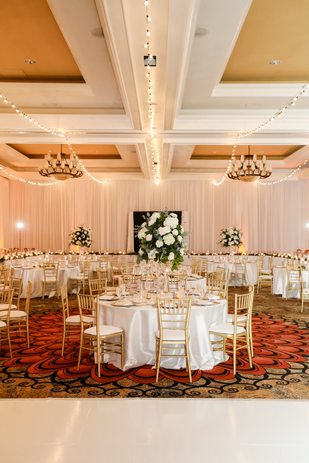 Elegant Timeless Wedding Reception Ballroom Decor, String Lights on Ceiling, Gold Chiavari Chairs, Tall White and Greenery Floral Centerpieces | Tampa Bay Wedding Photographer Lifelong Photography Studio | Clearwater Beach Wedding Venue Sandpearl Resort | Wedding Planner Blue Skies Weddings and Events | Wedding Florist Iza's Flowers
