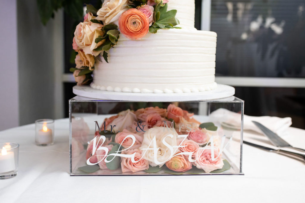 Square Clear Acrylic Cake Stand filled with Peach and Pink Fresh Flowers Roses with Custom Bride and Groom Name Decal