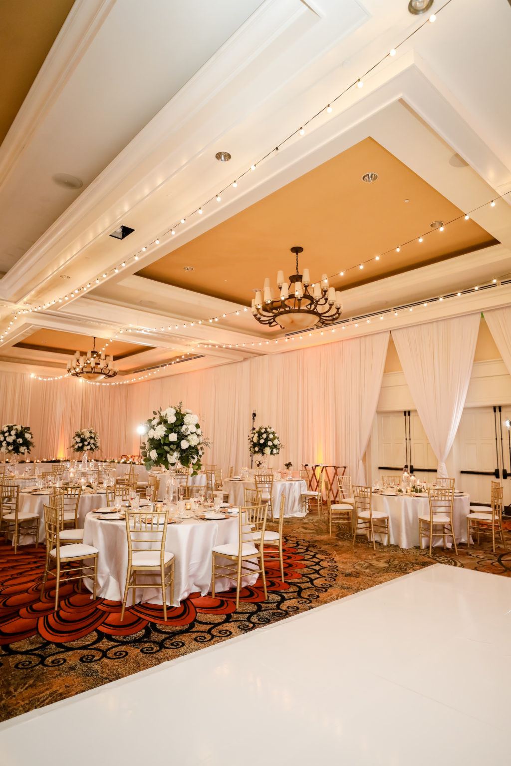 Elegant Timeless Wedding Reception Ballroom Decor, String Lights on Ceiling, Gold Chiavari Chairs, Tall White and Greenery Floral Centerpieces | Tampa Bay Wedding Photographer Lifelong Photography Studio | Clearwater Beach Wedding Venue Sandpearl Resort | Wedding Planner Blue Skies Weddings and Events | Wedding Florist Iza's Flowers