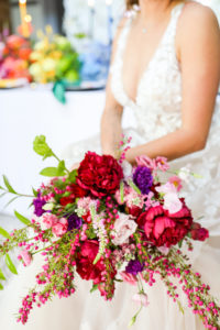 Colorful Modern Rainbow Gay LGBTQ+ Pride Wedding Reception Decor, Lesbian Bride Holding Wild Red, Purple and Pink Floral Bouquet | Tampa Bay Wedding Planner Stephany Perry Events