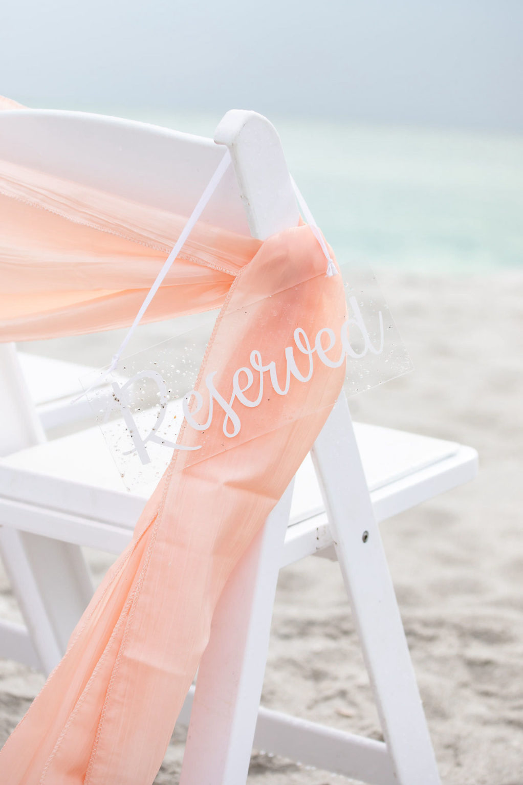 Sarasota Florida Beach Wedding White Folding Ceremony Chair with Acrylic Clear Reserved Sign and Peach Sash