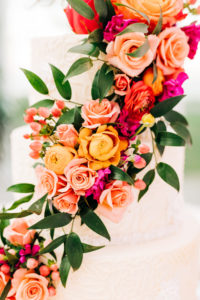 Elegant Three Tier White Wedding Cake with Vibrant Cascading Pink, Orange Roses and Greenery Flowers | Tampa Bay Florist Monarch Events and Design