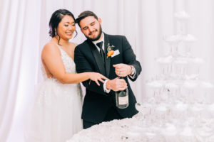 Elegant Bride and Groom Opening Bottle of Champagne for Champagne Tower