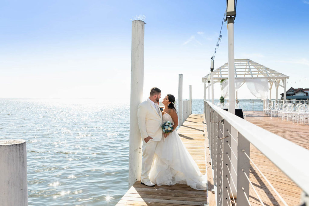 Waterfront Wedding Ceremony Portraits with Overwater Pier and White Pergola with Draping and Greenery | Tampa Wedding Venue The Godfrey