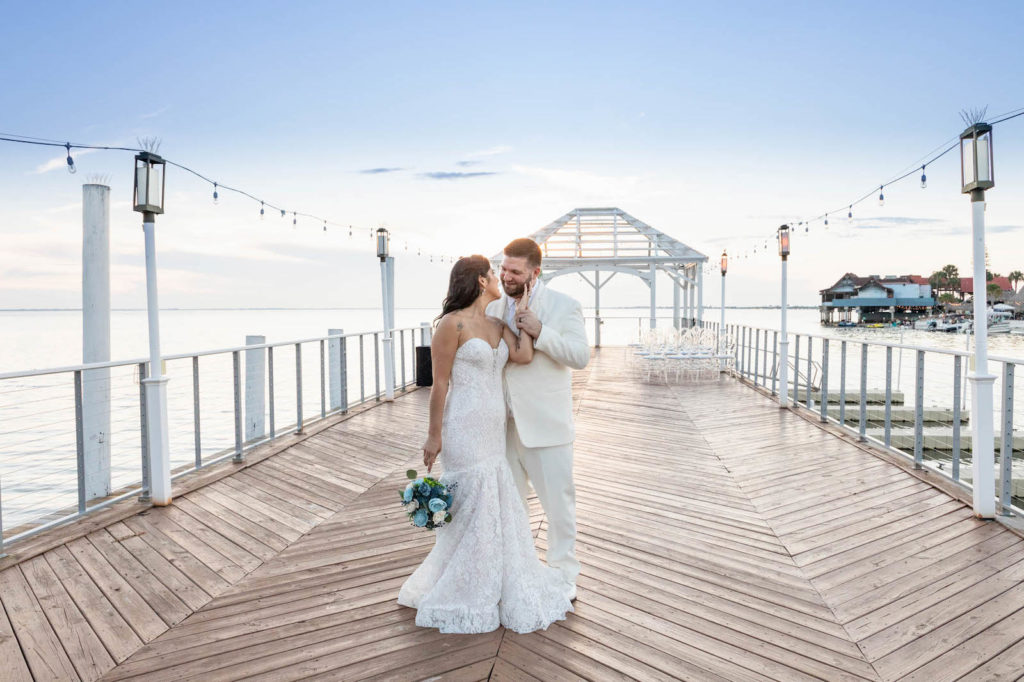 Waterfront Wedding Ceremony Portraits with Overwater Pier and White Pergola with Draping and Greenery | Tampa Wedding Venue The Godfrey