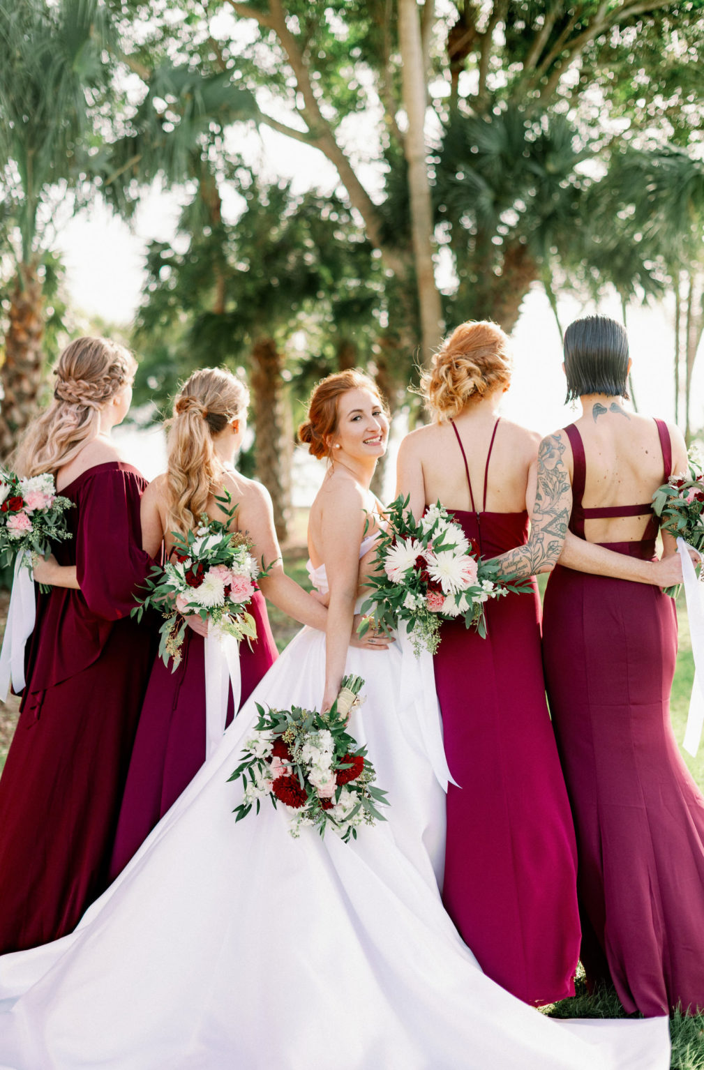 Bride and Bridesmaids in Mix and Match Burgundy Dresses Holding White, Blush Pink and Dark Red with Greenery Floral Bouquets | Tampa Bay Wedding Photographer Dewitt for Love Photography