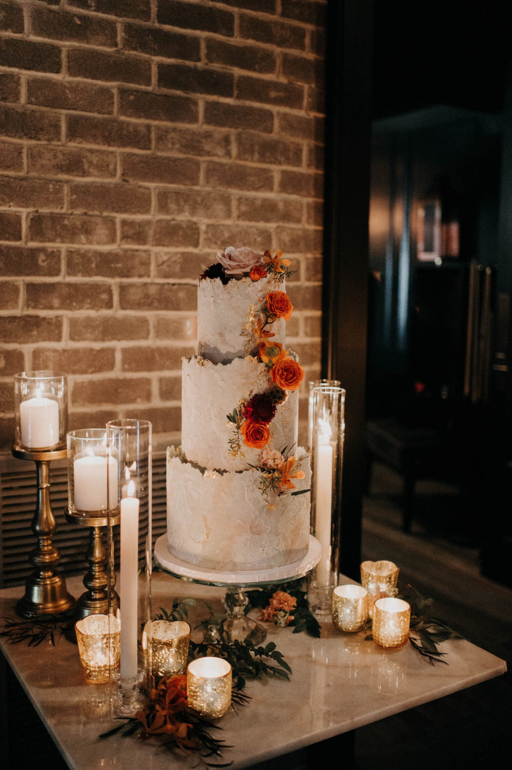 Three Tier White and Gold Textured Wedding Cake with Burnt Orange Roses, Candlesticks and Mercury Gold Votives | Wedding Venue Urban Stillhouse St. Pete | Tampa Bay Wedding Cake The Artistic Whisk