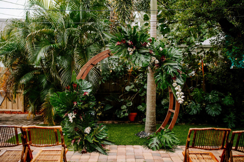 Outdoor Florida Wedding, Backyard Ceremony with Jungle Inspired Decor with Bamboo Circle Arch and Folding Chair Rentals, Bright Greenery with pops of Pink Florals and White Orchids | St. Petersburg Wedding Planner Parties A'La Carte