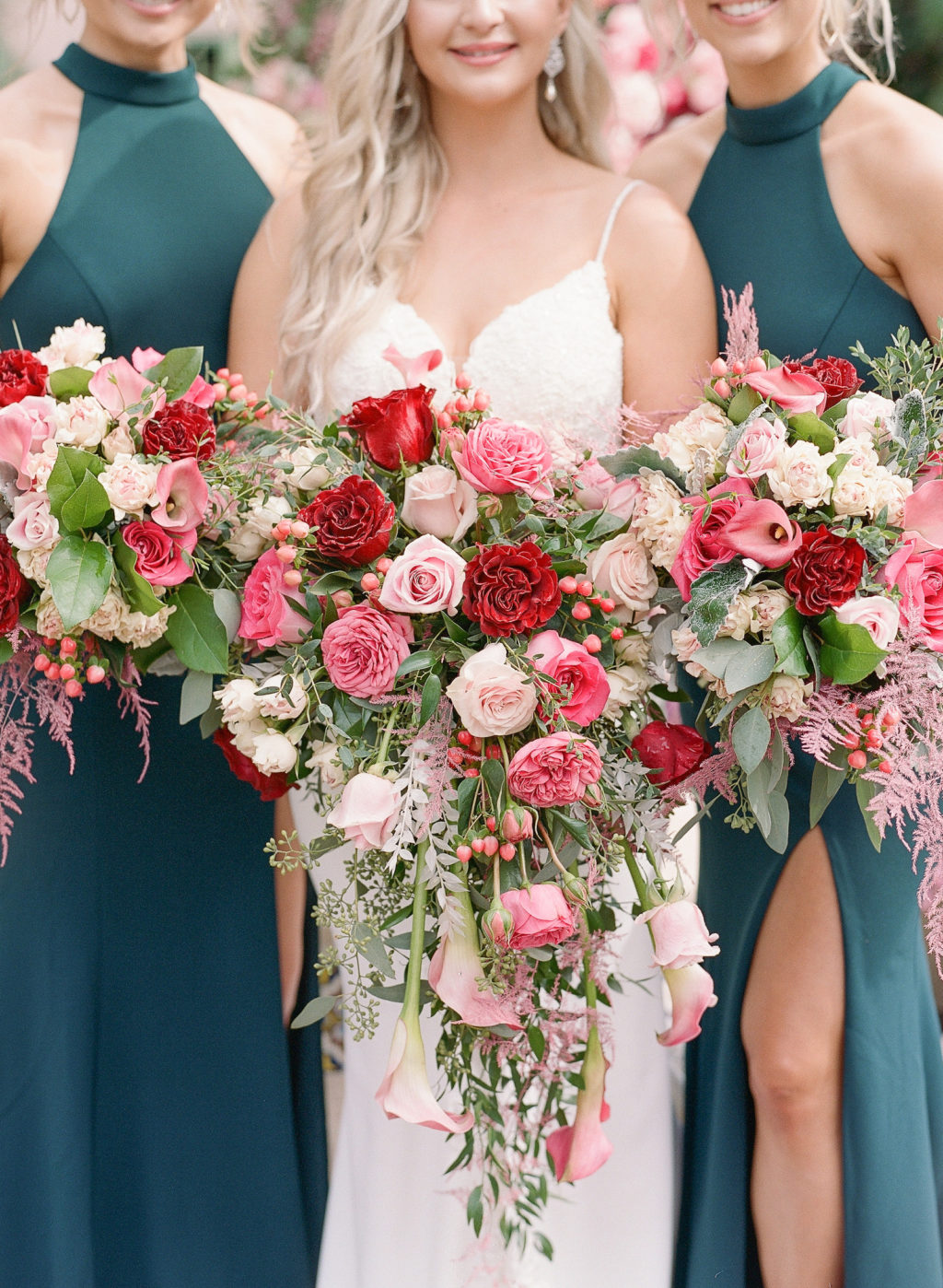 Elegant Bride with Bridesmaids in Emerald Green Dresses Holding Red, Pink and White Roses with Greenery Floral Bouquets Standing in Front of Courtyard Water Fountain with Floral Peacock Statue with Pink, White and Purple Lush Floral Tail | St. Pete Wedding Venue The Vinoy Renaissance | Tampa Bay Wedding Hair and Makeup Femme Akoi Beauty Studio