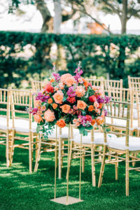 Outdoor Garden Wedding Ceremony Decor, Gold Chiavari Chairs, Gold Stands with Vibrant Colorful Purple, Pink, Orange Roses, Red and Greenery Lush Floral Arrangement | Wedding Venue Tampa Garden Club | Wedding Florist Monarch Events and Design | Wedding Rentals Kate Ryan Event Rentals