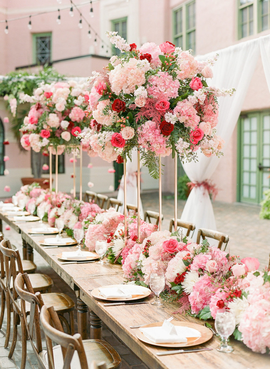 Elegant Garden Theme Wedding Reception Decor, White Drapery with Hanging Pink Flowers, Long Wooden Feasting Table with Wooden Cross Back Chairs, Tall Pink, Ivory and Red Floral Centerpiece, Lush Flowers Table Runner, Gold Chargers | St. Pete Wedding Venue The Vinoy Renaissance