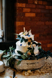 Vintage Inspired Wedding Cake, Two Tier White Cake with Floral Accessories, Greenery and Blush Pink Flowers Cascading Down the Cake, Humor Cake Topper of Bride Dragging Groom To The Aisle, Cake Serving 55 Guests | Tampa Bay Wedding Venue J.C. Newman Cigar Co. in Ybor City Florida