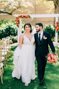 Classic Outdoor Garden Ceremony, Bride and Groom Holding Vibrant Colorful Pink, Orange and Red Bridal Floral Bouquet Walking Together Down the Aisle | Tampa Bay Wedding Florist Monarch Events and Design | Wedding Venue Tampa Garden Club
