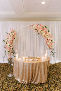 Classic Wedding Reception Decor, Sweetheart Table Gold Shimmer Linens, Candlelight, Champagne Bottle, White Draping, Circle Arch with Blush Pink and Ivory Roses | Florida Wedding Planner Parties A'La Carte | Tampa Bay Luxury Floral Designer Bruce Wayne Florals | Over the Top Rental Linens | Furniture Rental A Chair Affair