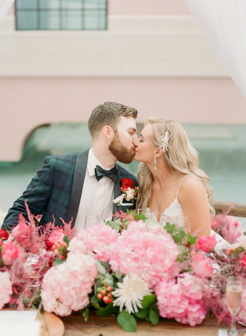 Elegant Bride and Groom Kissing at Wedding Reception with Lush Pink Hydrangeas Floral Decor | Tampa Bay Wedding Hair and Makeup Femme Akoi Beauty Studio