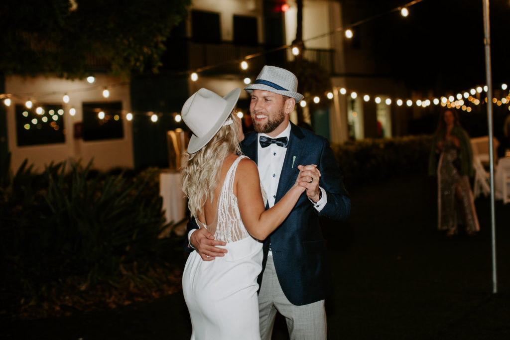 Romantic Bride Wearing Plunging Open Back Wedding Dress and Cowboy Monroe Rancher Hat, Groom in Emerald Green Tuxedo Jacket and Fedora Hat | St. Pete Wedding Venue Postcard Inn on the Beach | Wedding DJ Grant Hemond and Associates