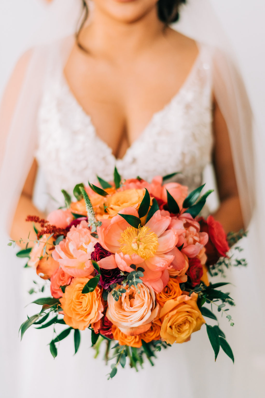 Tampa Bay Bride in V Neckline Lace Wedding Dress Holding Vibrant Colorful Pink and Orange Roses Floral Bouquet | Wedding Florist Monarch Events and Design